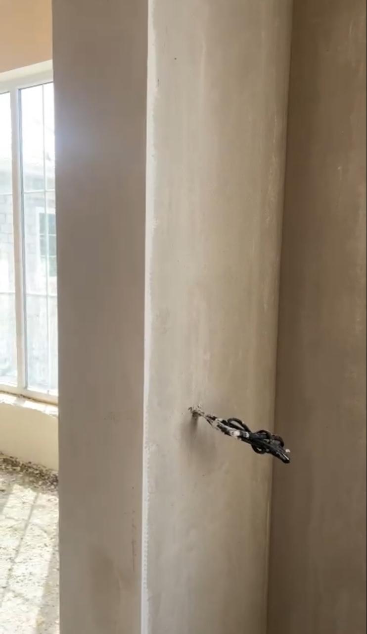 Коридор со свежей штукатуркой, открытыми проёмами и деревянным потолком.